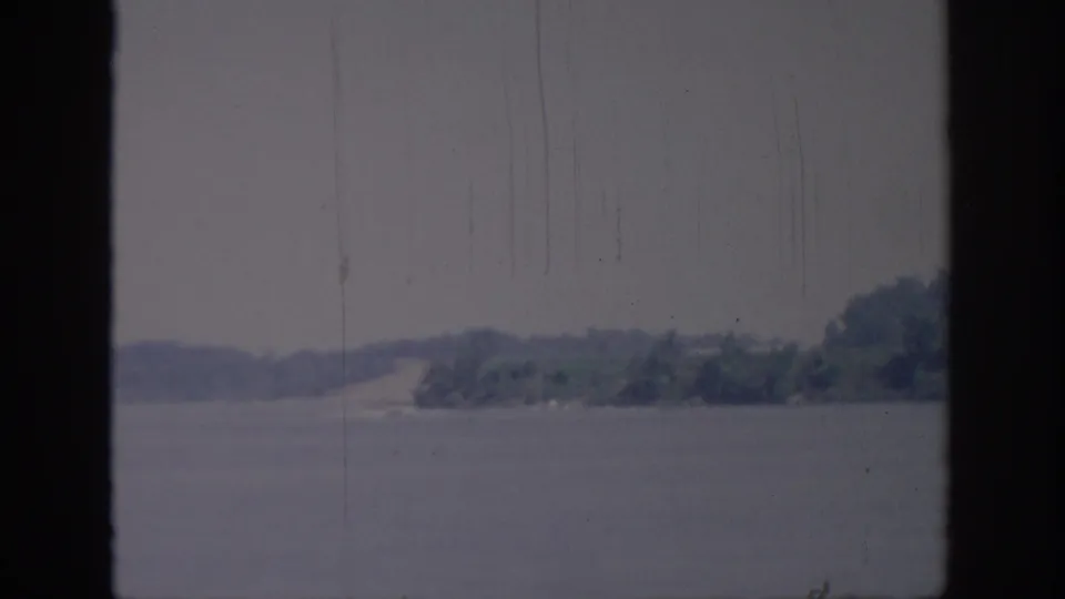 Oklahoma 1967 8mm still with soft-focus water, low shoreline, and trees along the far bank.