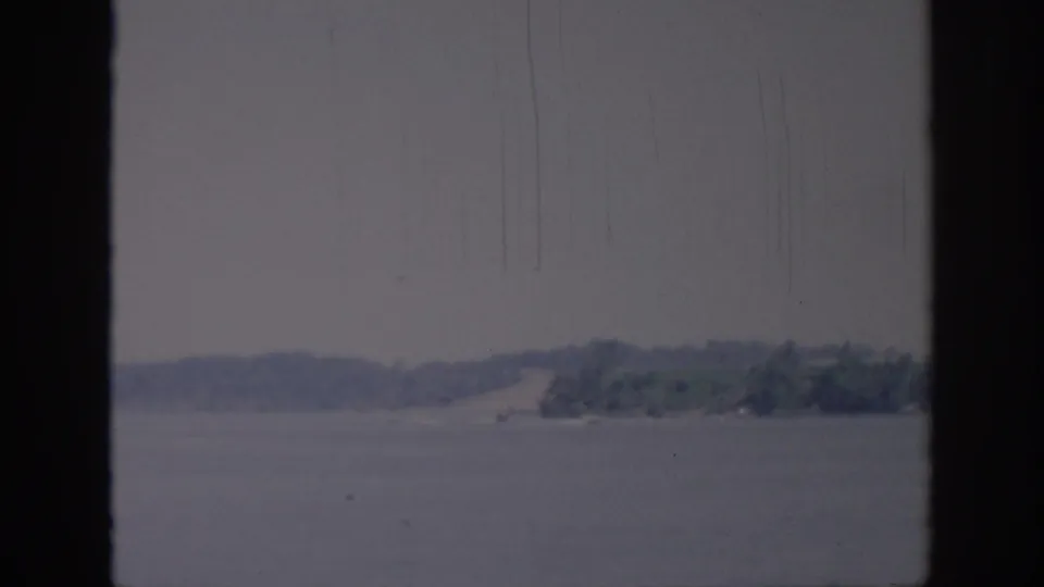 Final 1967 Oklahoma frame holding on water and a distant wooded shore, with aged 8mm texture visible.