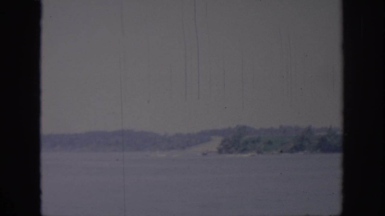 1967 Oklahoma 8mm home-movie frame showing a hazy lake and distant shore seen through a dark window frame.