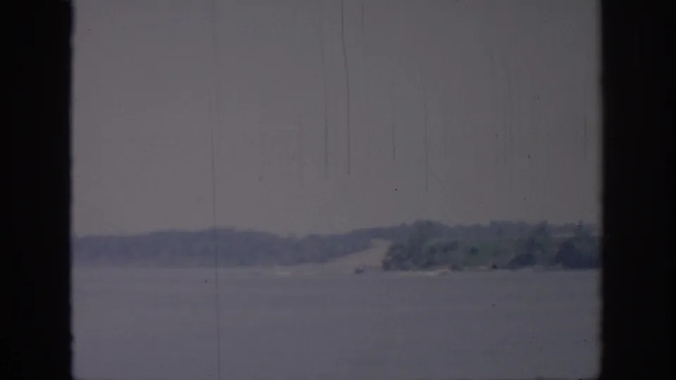 1967 Oklahoma 8mm home-movie frame showing a hazy lake and distant shore seen through a dark window frame.