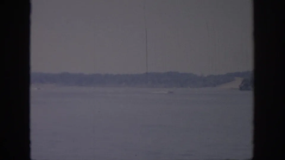1967 Oklahoma lake scene with a small speedboat moving across the water near a low wooded shoreline.