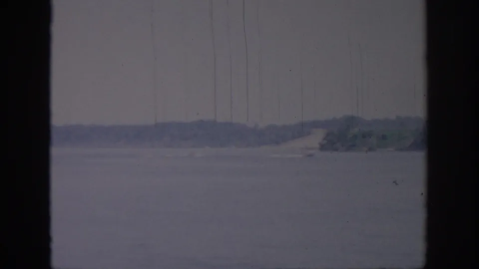 1967 Oklahoma lake scene with muted blue-gray water, distant wooded shoreline, and heavy dark framing from the shooting position.