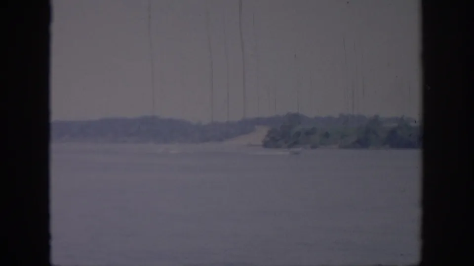 Soft 8mm Oklahoma lake view from 1967, showing open water, a distant wooded bank, and visible film scratches.