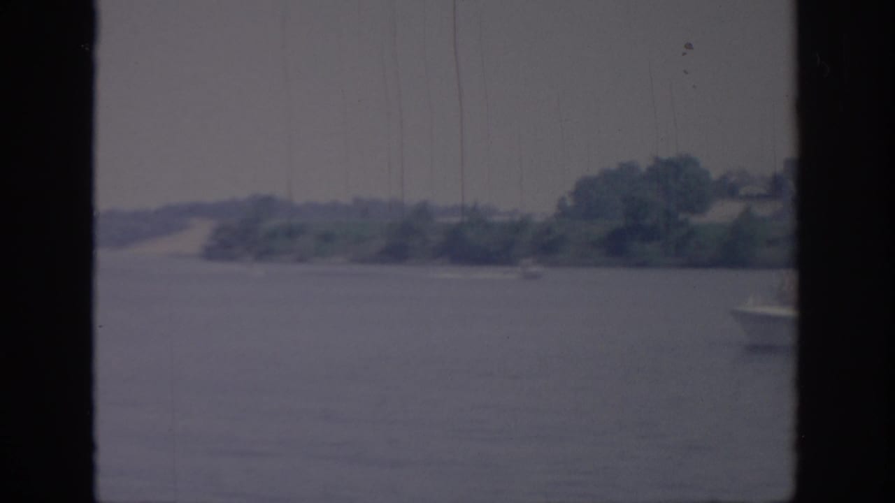 Wide water view with distant shore and a small boat just entering at the right edge.