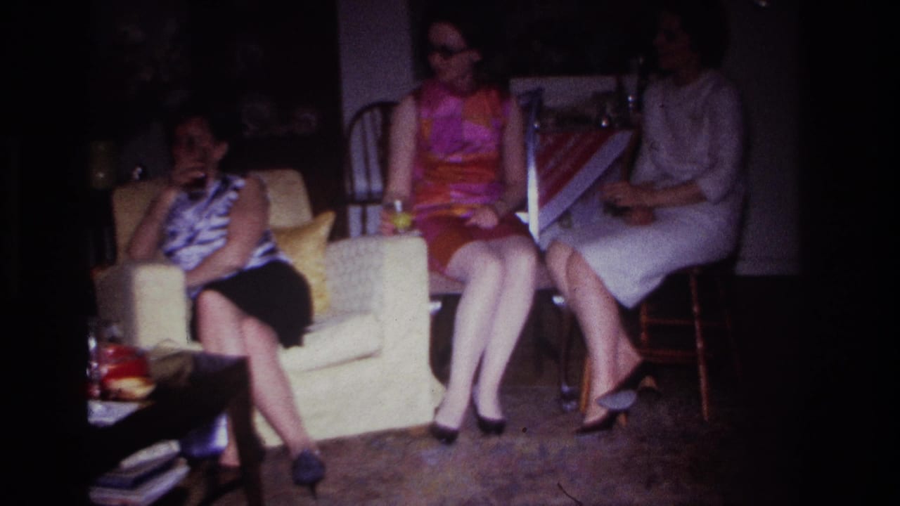 Three adult women in 1960s attire sit in a Rockaway Beach living room, with drinks and furniture visible in dim 8mm footage.
