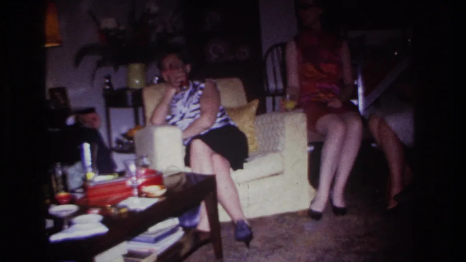 The final frame shows the women seated in the Rockaway Beach living room, with a coffee table, lamp, and drinks in the foreground.