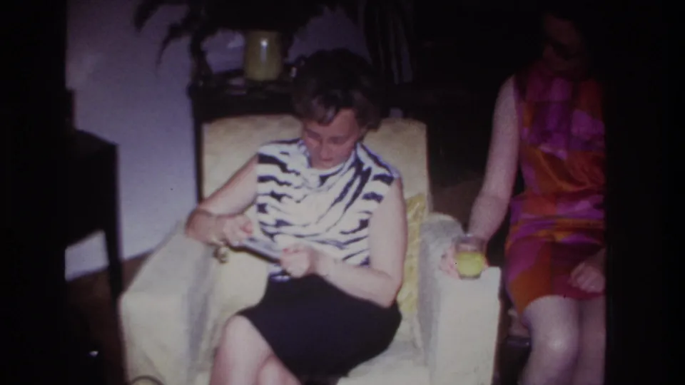 Rockaway Beach 1967 interior frame showing a woman in a zebra-print top reviewing photographs as another woman sits close by with a glass.