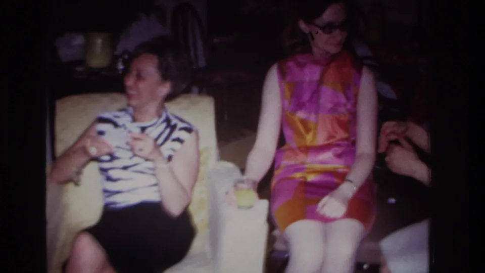 1967 Rockaway Beach frame of two women seated in a private interior, with one laughing and another holding a drink.