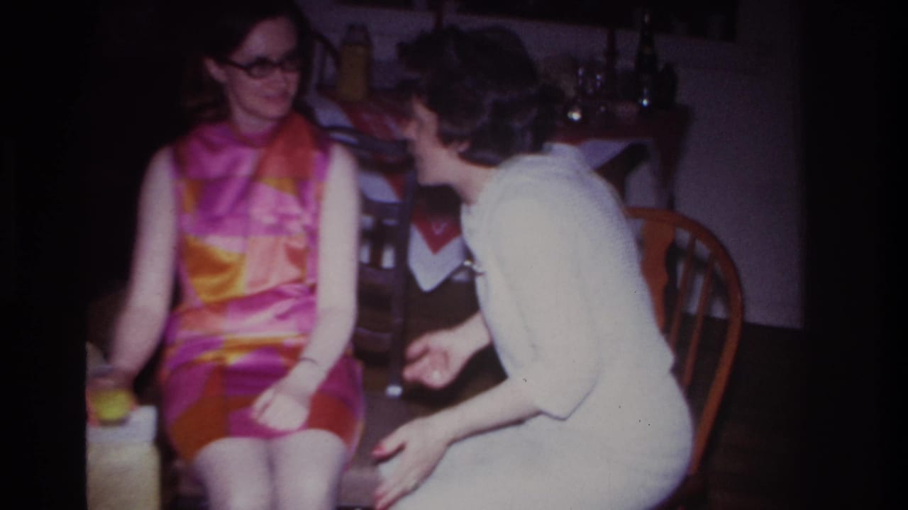 In a 1967 Rockaway Beach home interior, two adult women sit close together during a conversation at a small gathering.