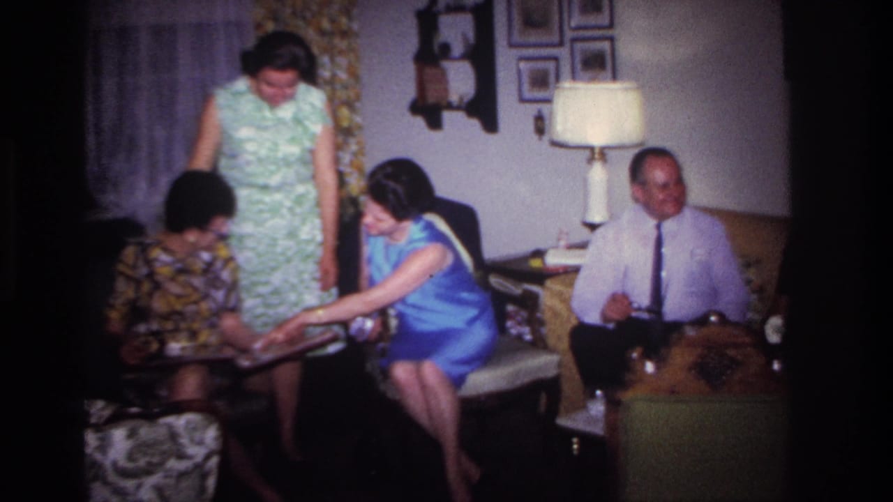 Woman in blue leans forward to show a seated woman something in a photo album.