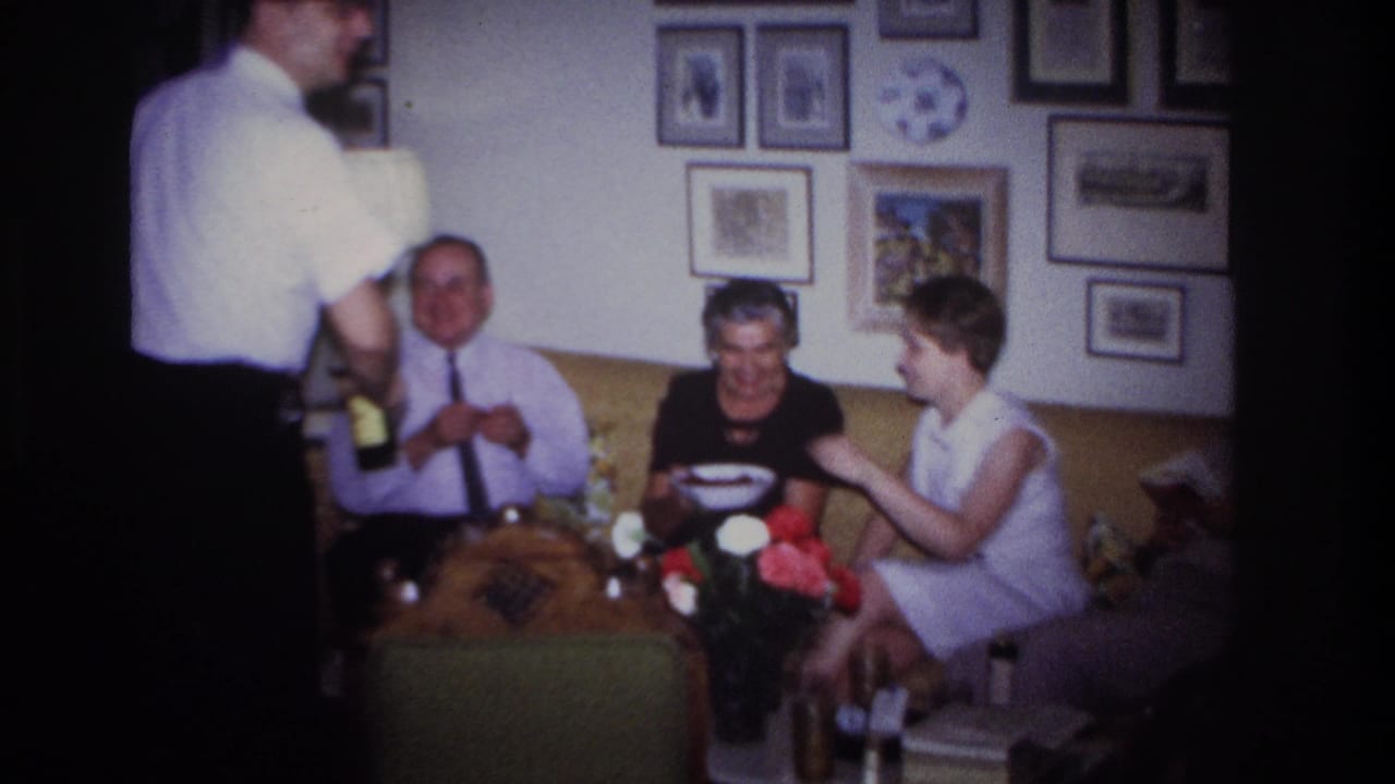 Adults sit together on a yellow couch in a private Rockaway Beach living room while a man in a white shirt stands with bottles.