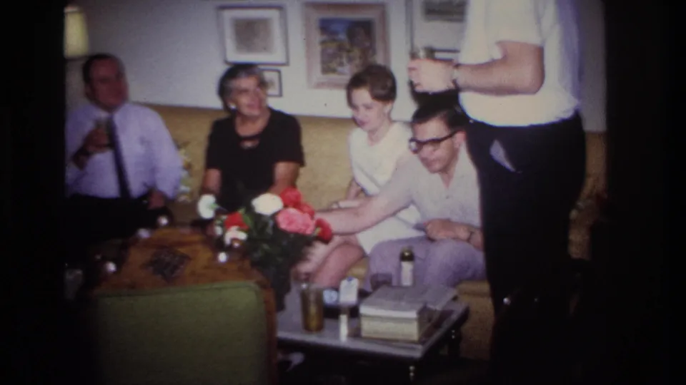 1967 Rockaway Beach home-movie view of adults socializing around a coffee table in a private living room.