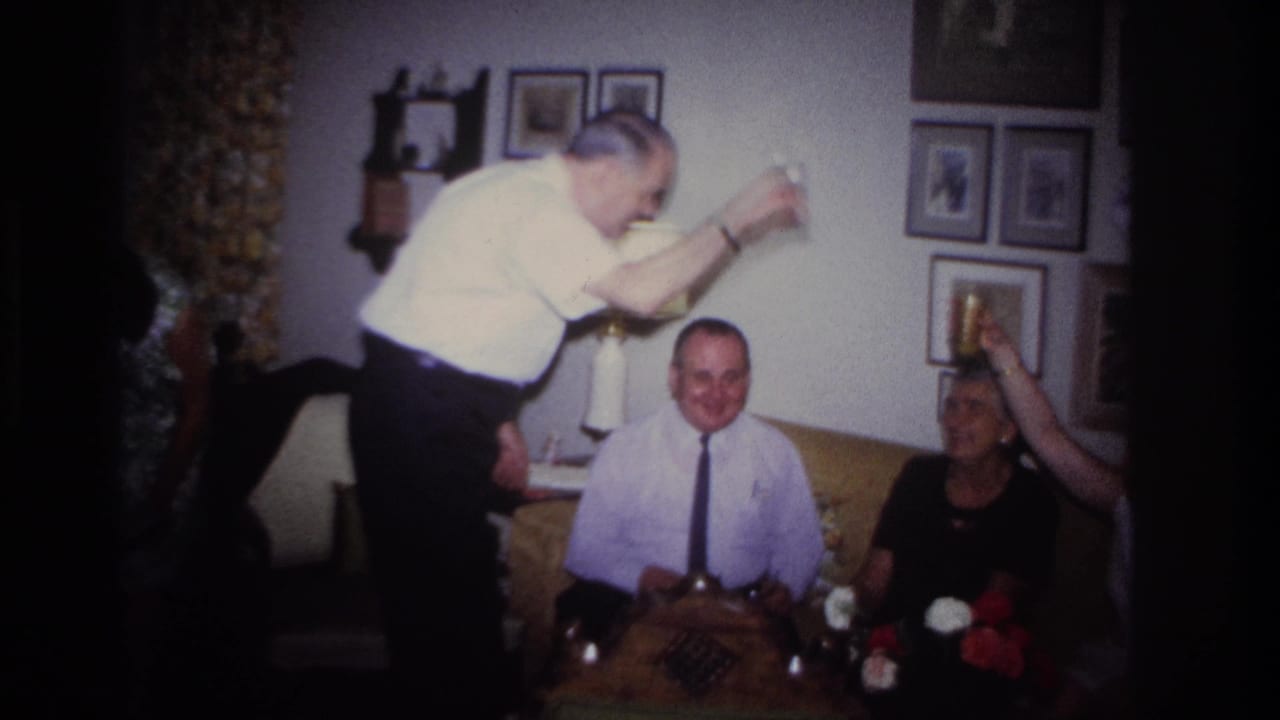 Rockaway Beach 1967 frame of a man lifting a drink above seated guests during a home gathering in a decorated living room.