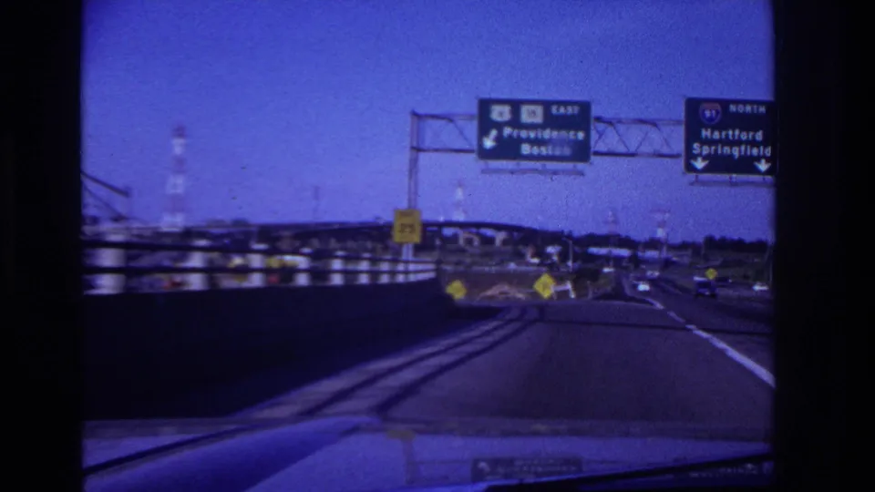 Highway POV with overhead signs for Providence, Boston, Hartford, and Springfield, plus lane markings, guardrails, and distant traffic.