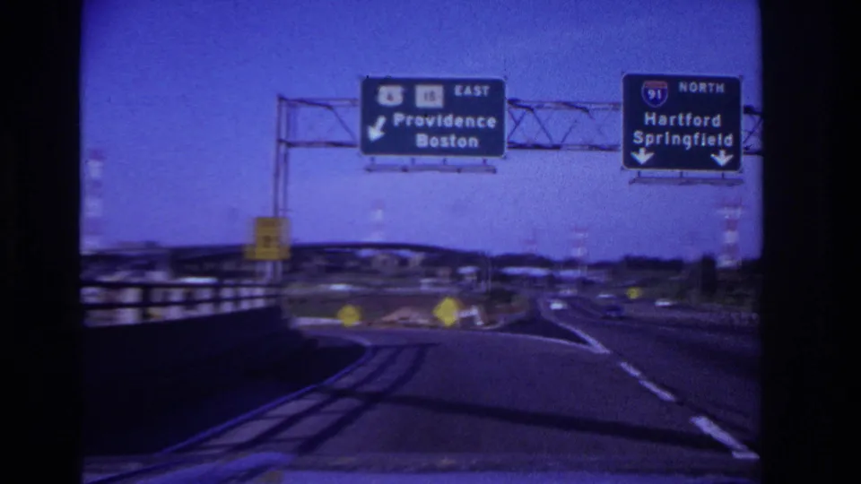 1967 8mm driving view on a multi-lane highway with overhead signs directing toward Providence, Boston, Hartford, and Springfield.
