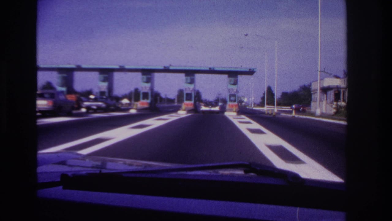 Car windshield view nearing toll booths with vehicles in nearby lanes.