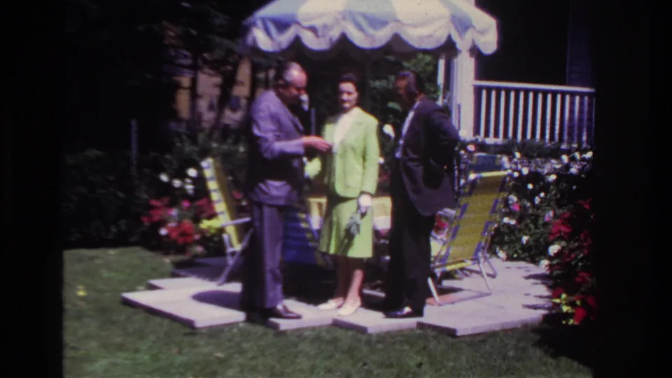 The final frame shows the three adults still gathered under the umbrella in the Rockaway Beach garden setting, with flowers and chairs around them.
