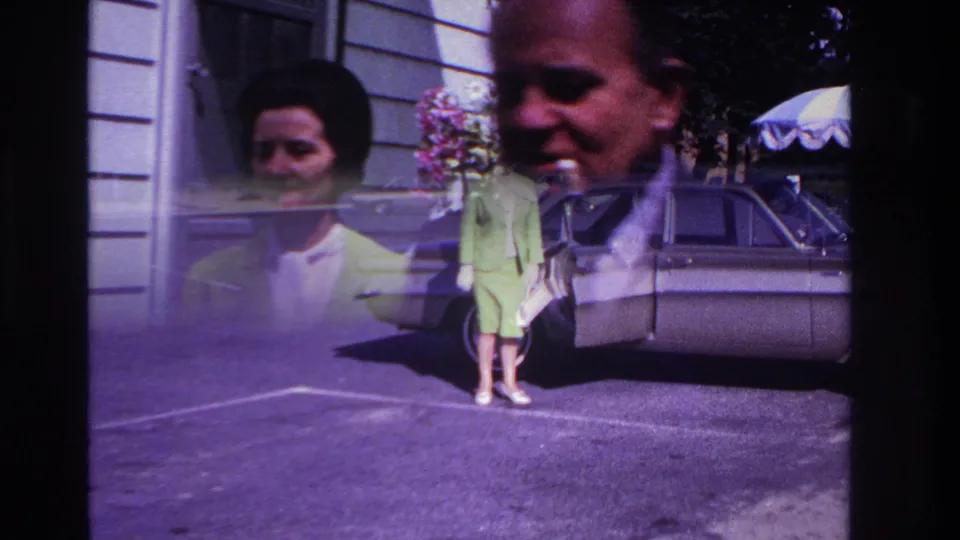 1967 Rockaway Beach frame showing the woman near a parked 1960s sedan, with visible double exposure or overlap from the film scan.