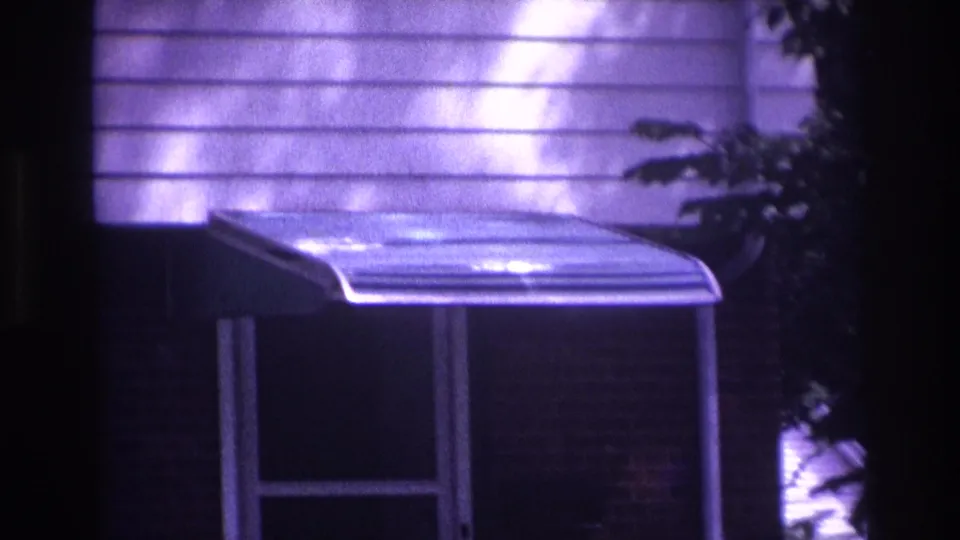 Purple-tinted 1967 Rockaway Beach frame showing residential siding, a small awning, porch details, and a partial figure near the edge.