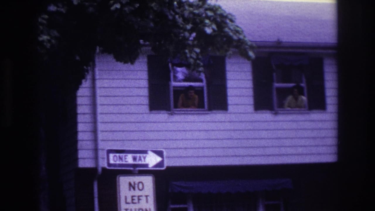 Rockaway Beach 1967 home-movie frame showing two people at second-story windows above One Way and No Left Turn signs.