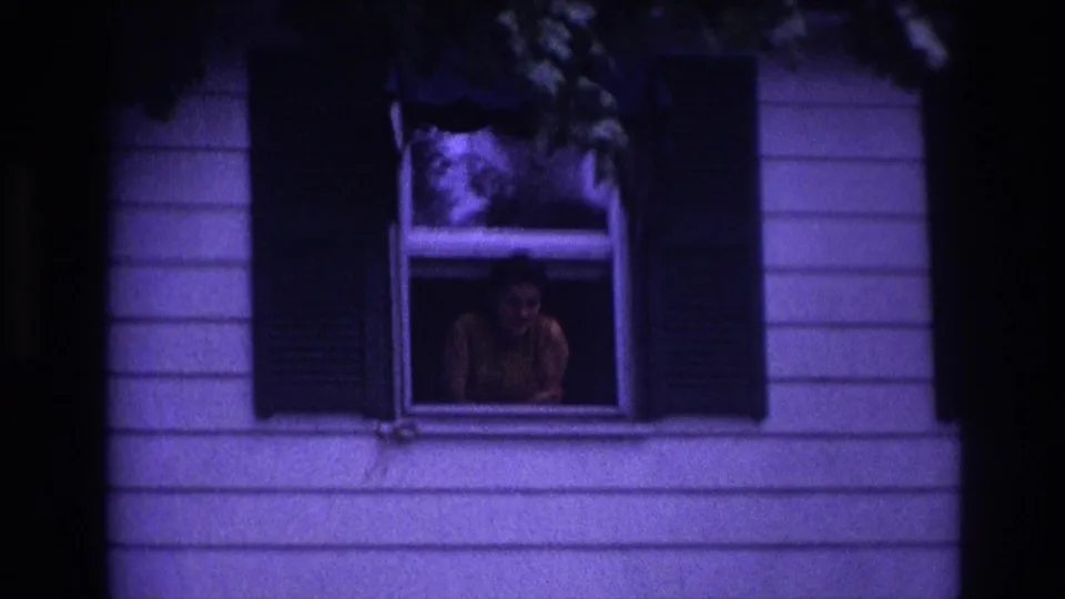Rockaway Beach 1967 frame showing a person at a second-story window of a clapboard house, tinted by aged 8mm color.