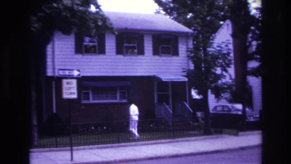 Final 1967 Rockaway Beach frame showing the man in white moving past the fenced residential house under visible upstairs window figures.