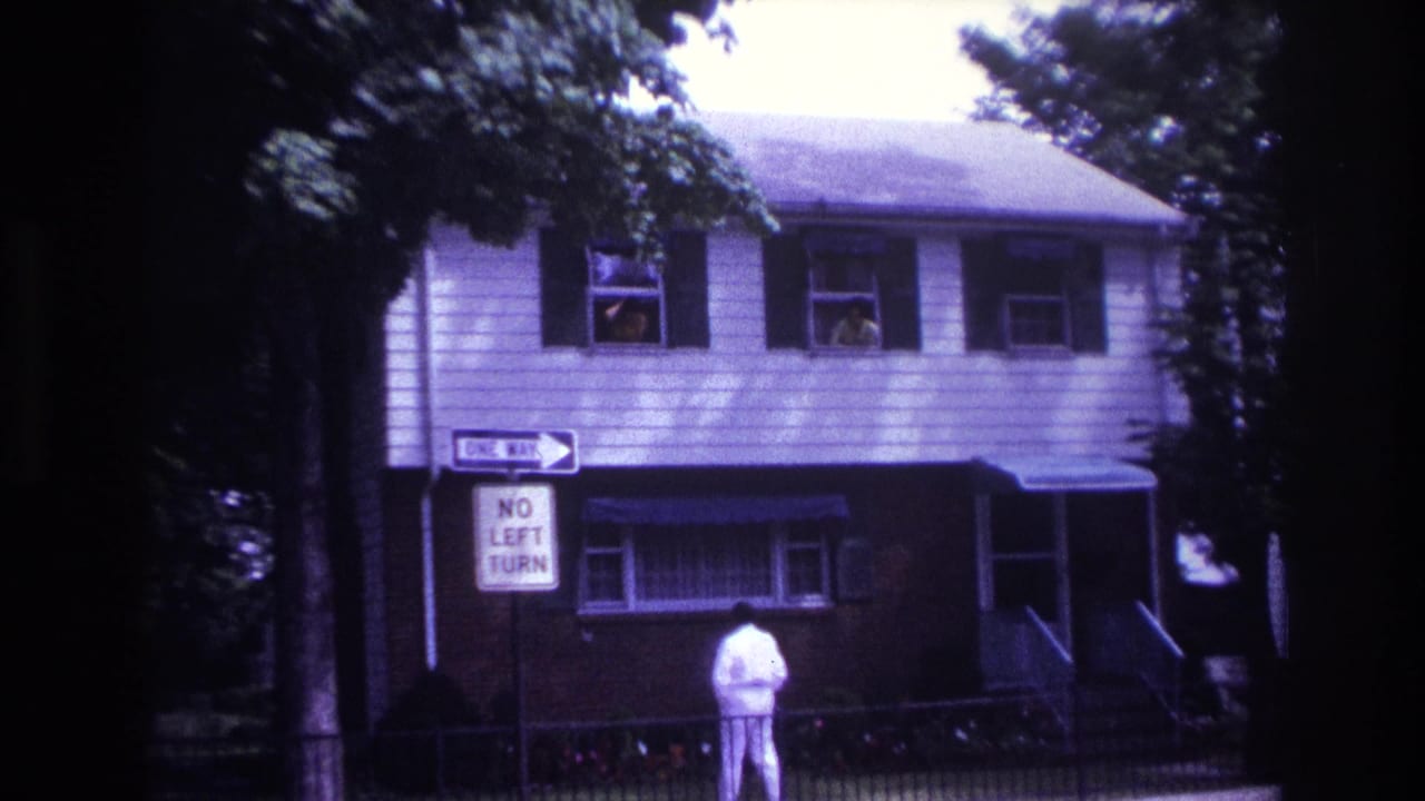 Rockaway Beach residential street frame with a man in white below upstairs windows and posted traffic signs.
