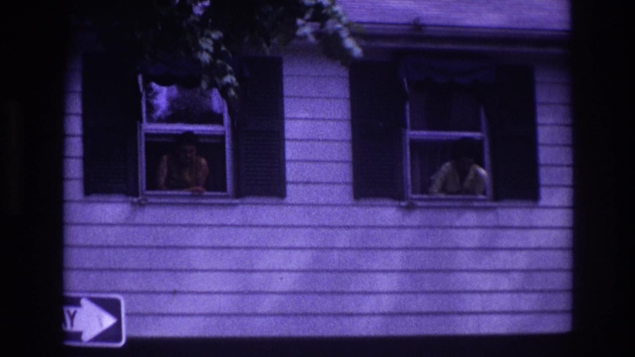 Two adult women appear in separate upper windows of a white-sided house with dark shutters.