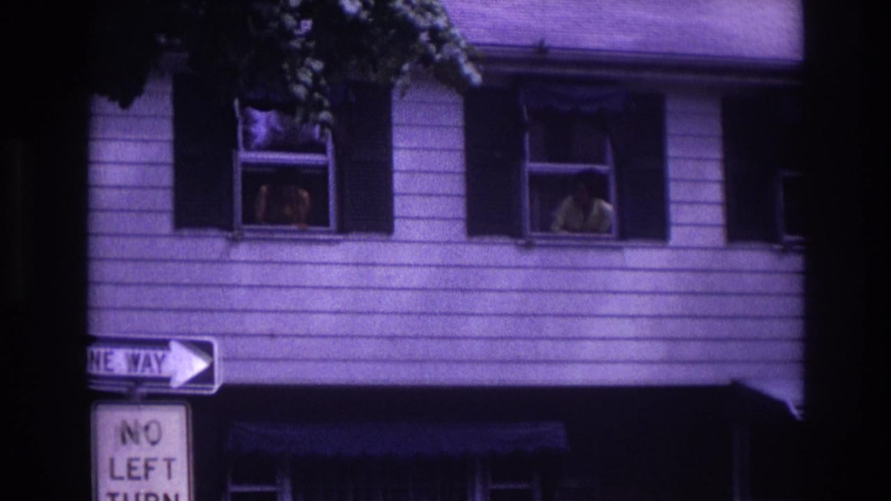 1967 Rockaway Beach frame with upstairs window figures, dark shutters, and a one-way sign partly visible below.