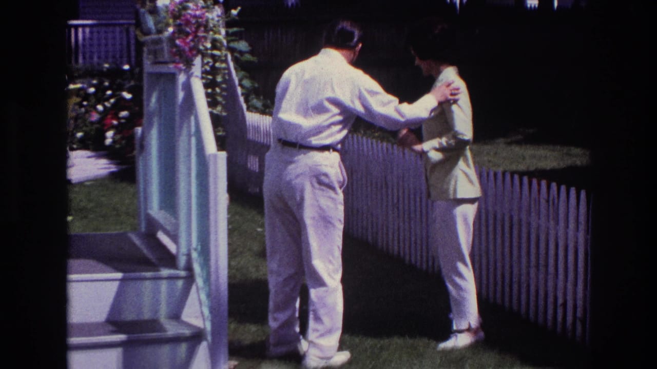 In Rockaway Beach home-movie footage, a man in light clothing steadies a woman near white steps and a picket fence.