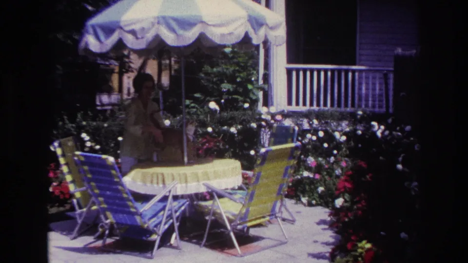 A Rockaway Beach patio scene shows a table, striped lounge chairs, flowers, porch railing, and a scalloped umbrella.