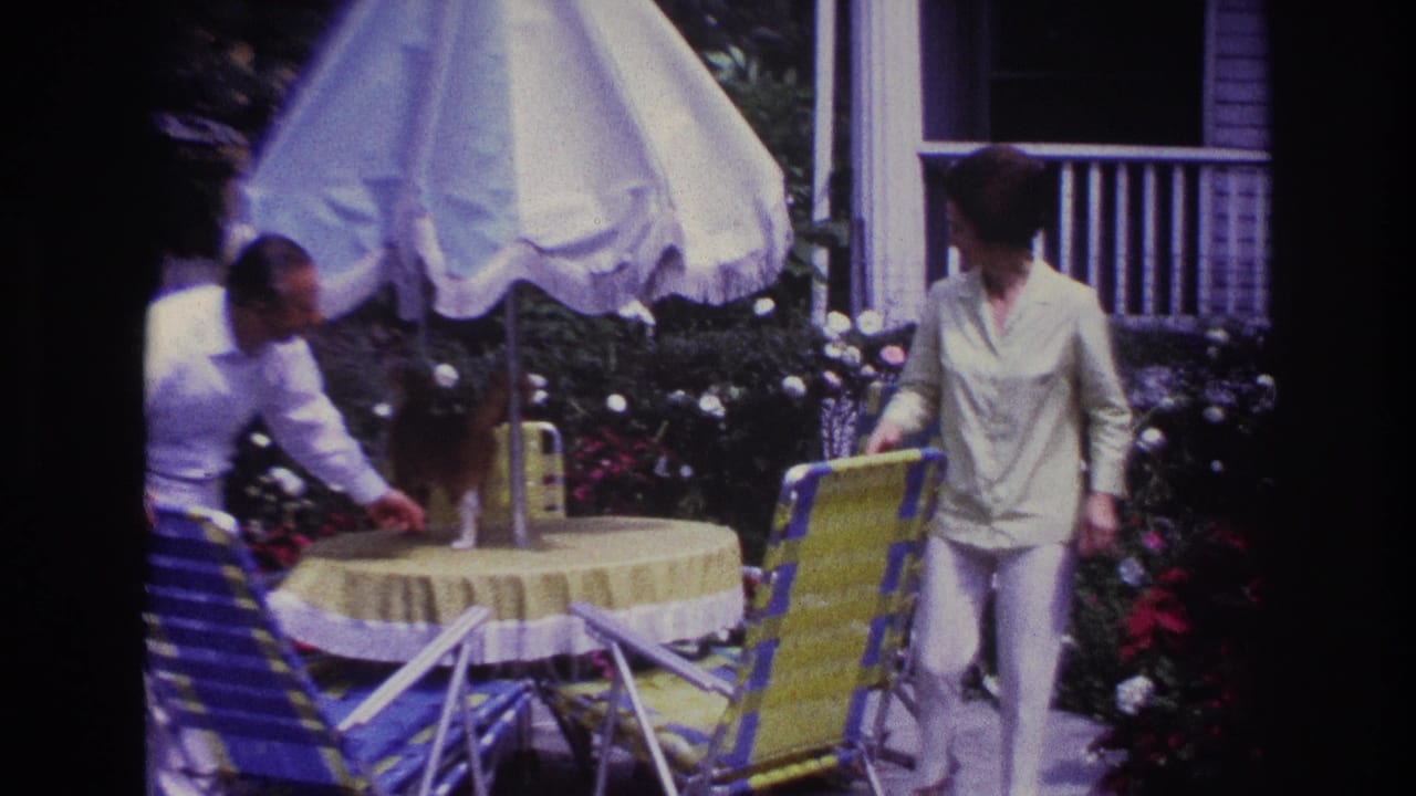 Man and woman adjusting a patio table and striped chair under a white umbrella.