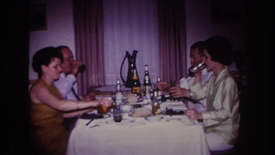1967 Rockaway Beach dinner scene with guests eating and drinking at a white-clothed table in a private interior.
