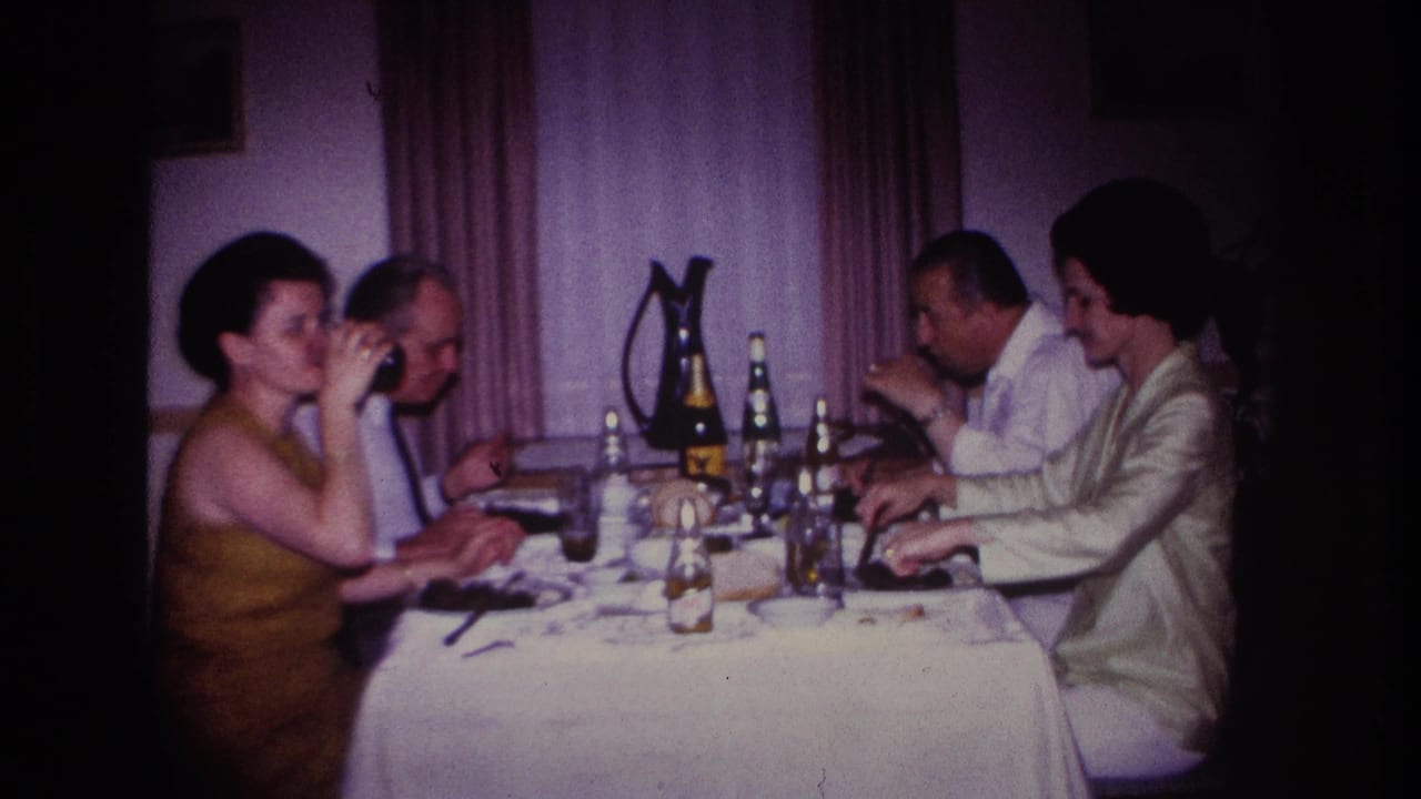 Four adults continue eating and drinking at a restaurant table with bottles, glasses, plates, and a dark pitcher.
