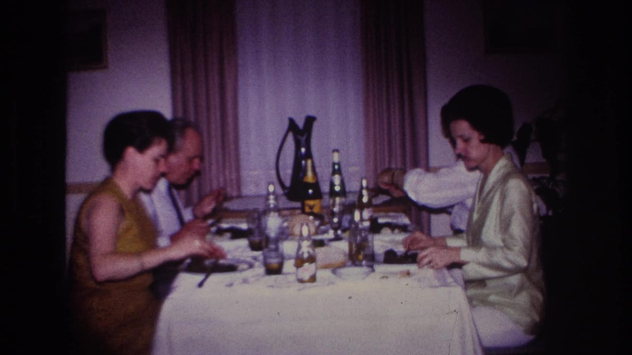 Four adults sit around a table with drinks, plates, bottles, and a pitcher.