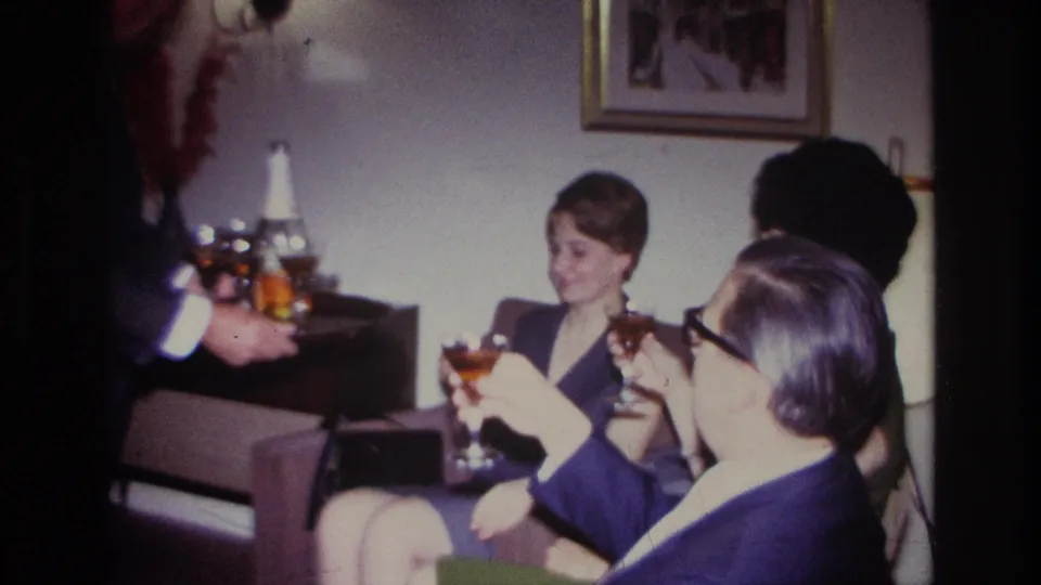 1967 Rockaway Beach living-room gathering with adults holding cocktail glasses as a suited man serves from a tray.