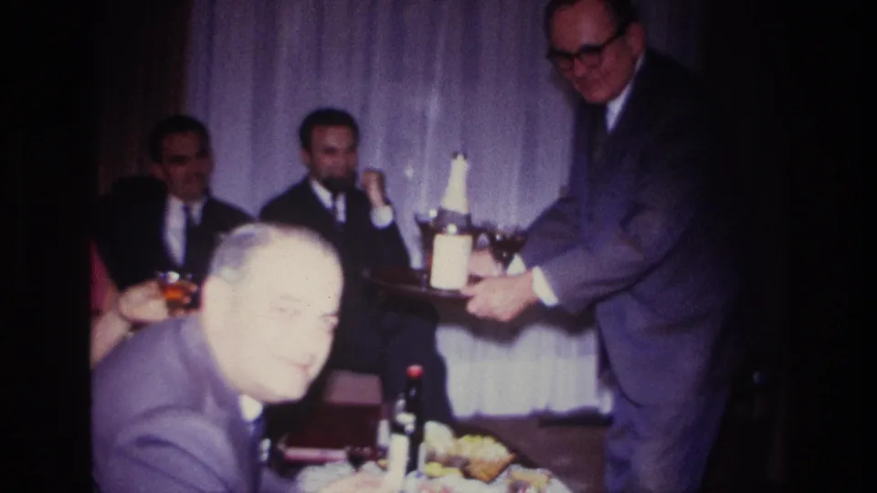 Home-movie frame from a 1967 Rockaway Beach party with a foreground guest and drinks being served indoors.
