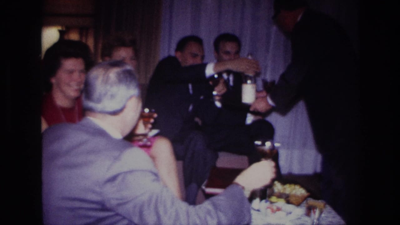 A server pours from a bottle near seated guests holding drinks.