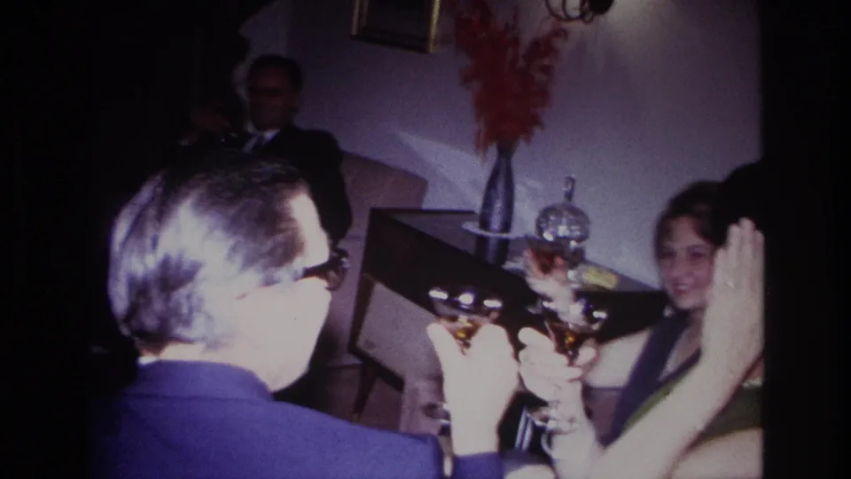 A smiling woman and other adults with cocktail glasses appear in a 1967 Rockaway Beach home-party scene.