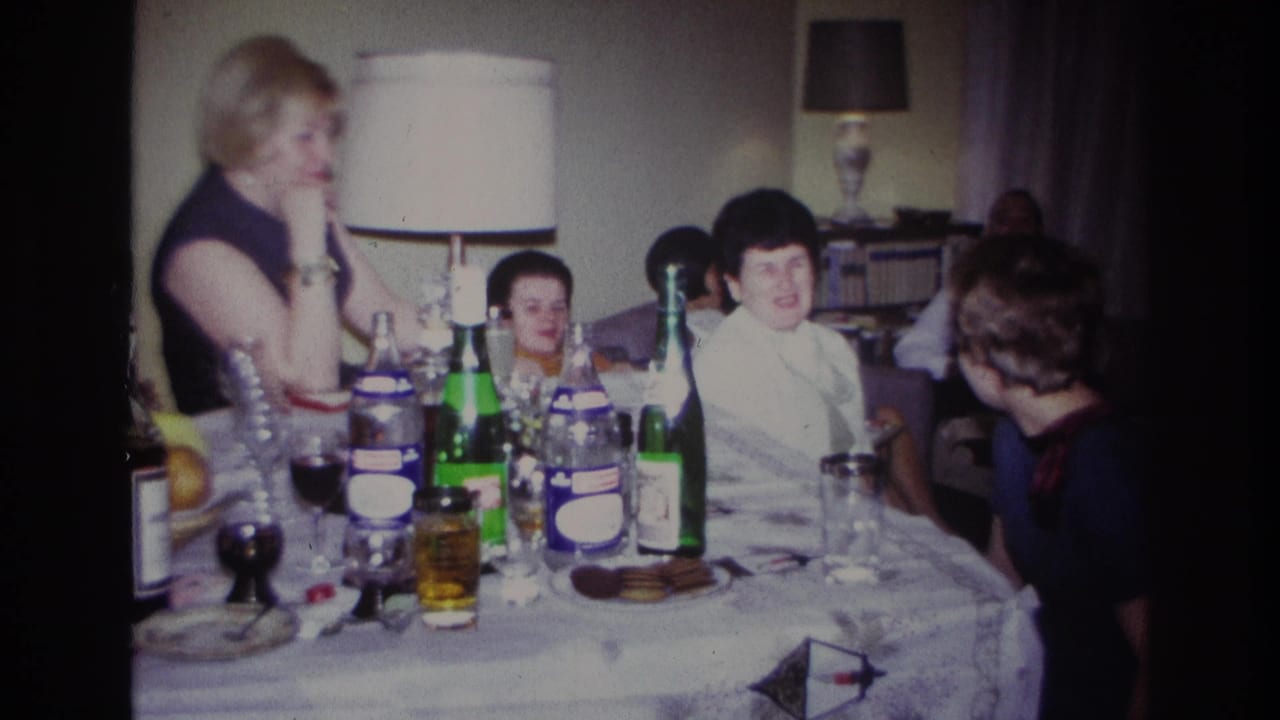 Adults gather around a table with bottles and glasses in a private interior.
