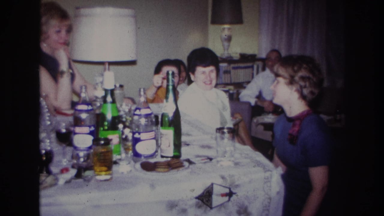 1967 Rockaway Beach frame with several adults seated at a table, including women in light and dark dresses near bottles and glasses.