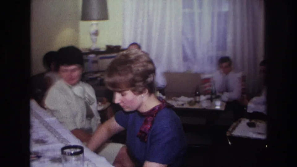 1967 Rockaway Beach frame showing a blonde woman at a piano, another woman beside her, and party guests seated in a private living room.
