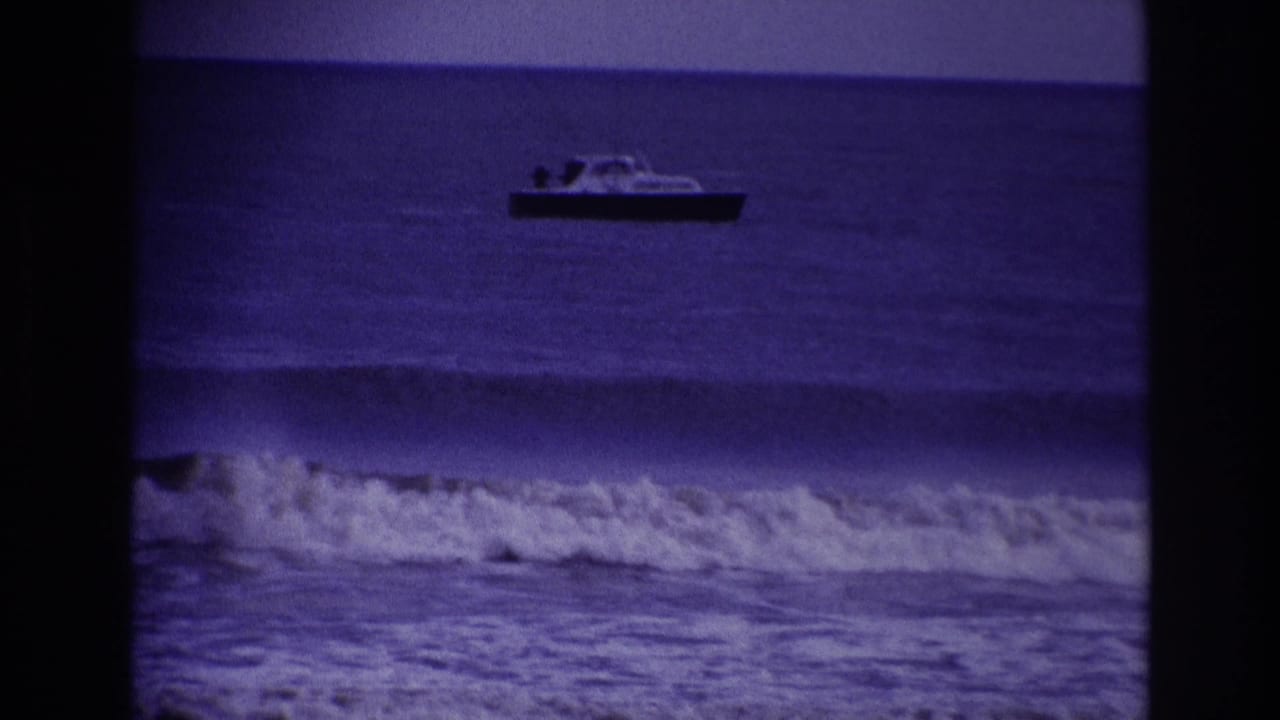 Distant motorboat on the ocean above a line of breaking surf.