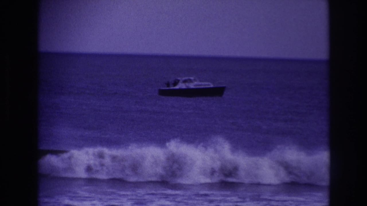Small boat offshore with a breaking wave in the foreground.