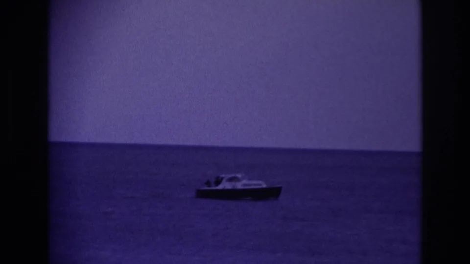 1967 Rockaway Beach home-movie frame holding on a small motorboat against open water and a quiet horizon.
