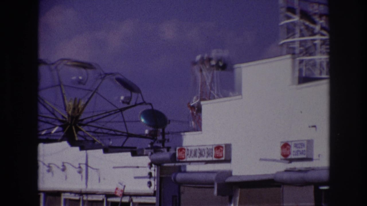 1967 Rockaway Beach view of a Ferris wheel partly visible above a white concession building with soda and custard signs.