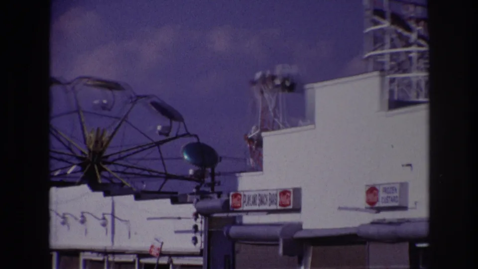 1967 Rockaway Beach view of a Ferris wheel partly visible above a white concession building with soda and custard signs.
