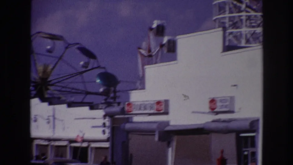 Rockaway Beach amusement frontage with the Ferris wheel, snack bar signs, and heavy dark frame edges from the film scan.