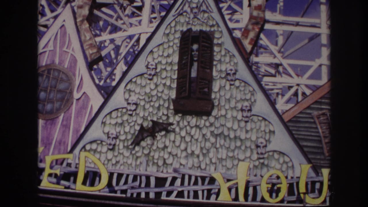 1967 Rockaway Beach home-movie frame showing a gothic amusement facade with skull ornaments, yellow letters, and roller-coaster framework.