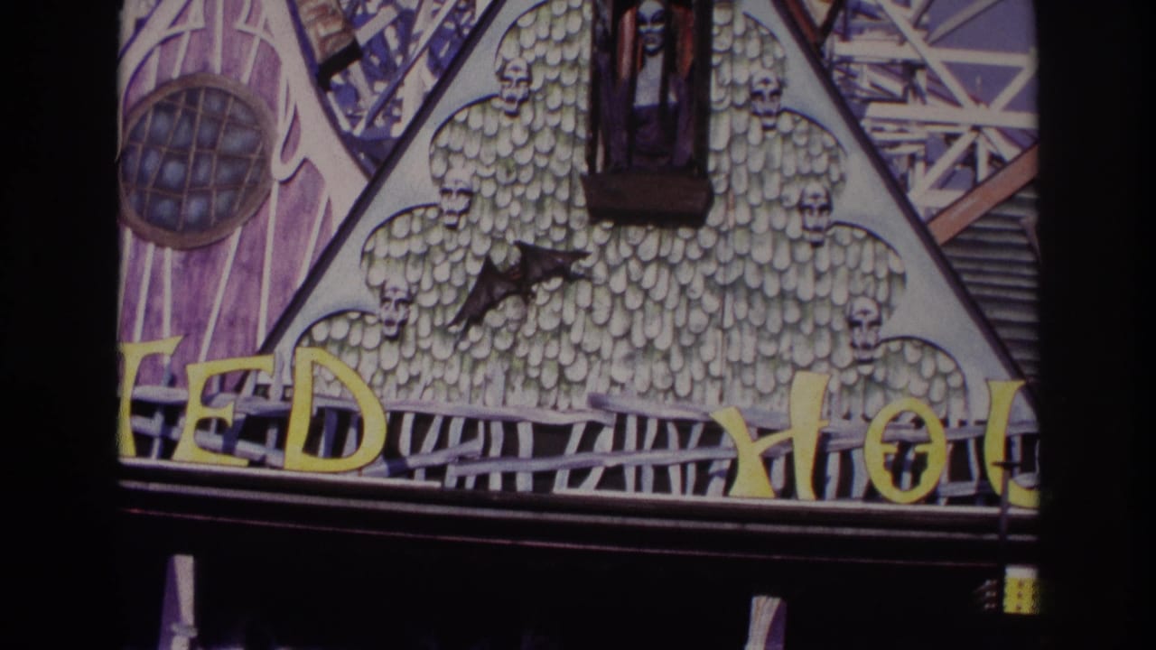 1967 Rockaway Beach home-movie frame showing the upper TEDDY HOUSE facade with yellow letters, skull motifs, and a black bat shape.